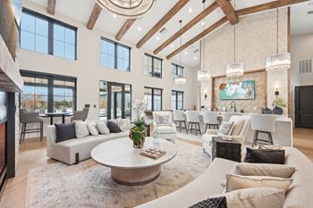 A large, well-lit living room with a variety of seating options and a central coffee table.